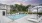 Pool area at our apartment and townhome community in Trumbull, featuring white umbrellas, reclining chairs, and a clubhouse. 