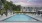 Pool area at our apartments in Trumbull, featuring white umbrellas, reclining chairs, and a clubhouse. 